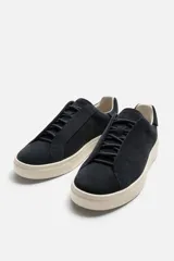 Zapatillas deportivas de hombre confeccionadas en cuero serraje color azul marino. Presentan cordonera oculta y suela de goma color crema de bajo volumen.