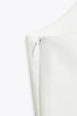 Top blanco de tejido elástico con escote cuadrado y tirantes anchos con lazos decorativos.