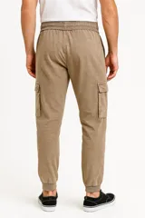 Pantalón babucha color beige con cintura elástica ajustable con cordón, bolsillos laterales y corte holgado.