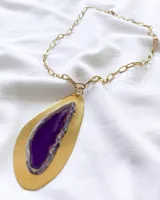 Collar con colgante de piedra agata en tonos morados y base de metal dorado.