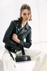 Campera de cuero ovino negra, estilo rocker, con cinturón, charreteras, solapas, cierres y detalles metálicos en frente y espalda.