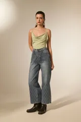 Pantalón de jean azul lavado, tiro alto, corte recto y largo. Presenta un patrón de rombos cosidos con hilo blanco o strass a lo largo de toda la prenda.