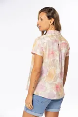 Camisa de manga corta con estampado floral en tonos pastel, cuello clásico y cierre frontal con botones.