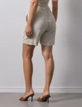 Short color beige de lino y rayón, con pretina elastizada, lazo de ajuste y bolsillos delanteros.