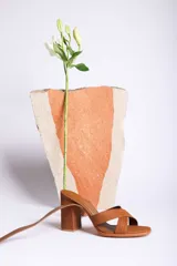 Sandalias de cuero color marrón con tiras cruzadas en el empeine, pulsera con hebilla al tobillo y tacón cuadrado.