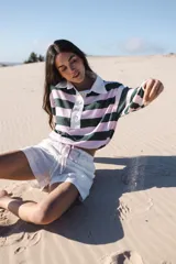 Remera tipo polo a rayas horizontales color borgoña y fucsia, con cuello clásico color crema, mangas largas abullonadas con puños elásticos y botones de nácar.