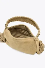 Mini bolso color beige de serraje, con flecos en los laterales, asa de mano trenzada y asa bandolera extraíble. Cierre con cremallera.