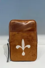 Cartera pequeña de cuero color marrón con cierre de cremallera y asa de mano. Presenta un diseño con una flor de lis bordada en el frente.