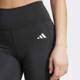 Calza corta deportiva Adidas color negro, de tiro alto y ajuste ceñido. Presenta un pequeño logo de tres barras en blanco en el muslo y un bolsillo oculto lateral.