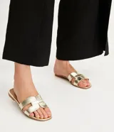 Sandalia plana de cuero sintético color negro, con puntera cuadrada y tiras anchas cruzadas en el empeine.