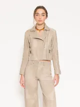 Chaqueta de cuero ovino color beige, con cuello clásico, cierre cruzado y múltiples bolsillos con cierre metálico. Presenta canesú y recortes matelaseados en codos.