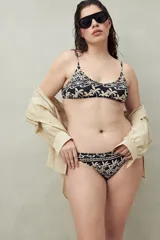 Bikini de dos piezas con estampado tropical en tonos beige y negro. El corpiño es de corte triangular con tirantes finos y la bombacha es de tiro medio.
