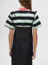 Vestido midi de denim algodón color marrón, con escote recto y tirantes finos ajustables con lazos. El corte es suelto y termina con un ruedo con semi-volado.