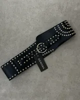 Faja ancha de cuero sintético color negro, con tachas plateadas y hebilla metálica circular.