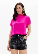 Blusa color fucsia con cuello alto y mangas cortas de corte relajado.