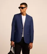Saco de traje azul cobalto, modelo social, con cuello solapa, abotonado delantero, bolsillos y mangas largas.