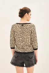Sweater de viscosa con estampado animal print de leopardo, mangas 3/4, cuello redondo y calce al cuerpo. Tiene guardas a contratono en puños, cuello y ruedo, e hilados de lurex.