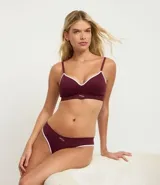Conjunto de lencería de dos piezas, color bordó, compuesto por un corpiño tipo bralette con tirantes finos y un calzón tipo bikini, ambos con ribete blanco contrastante.