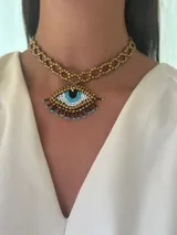 Collar corto tipo choker con diseño de ojo, elaborado con cuentas en tonos dorados y azules.