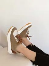 Championes de cuero color visón con cordones marrones, suela blanca y base color caramelo.
