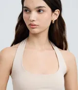 Blusa frente única color beige, con escote cuadrado y bretel ajustado en el cuello. Confeccionada en microfibra, es sin mangas y de corte ajustado.