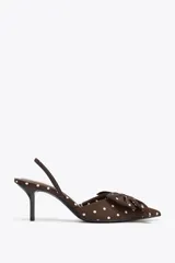 Zapato de tacón marrón con estampado de lunares blancos, tira trasera con elástico, punta fina y detalle de lazo en la parte delantera.