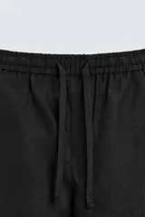 Pantalón de lino color marrón oscuro, de corte recto y relaxed fit. Tiene cintura elástica ajustable con cordón, bolsillos frontales y traseros de parche.