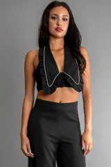 Top halter negro con cuello grande estilo solapa con borde de perlas sintéticas y cierre con botones en el frente.