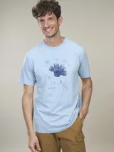 Remera celeste con estampado de un diseño floral en azul y texto en la parte inferior.