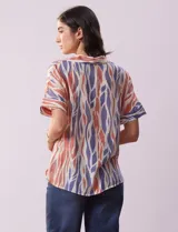 Blusa de gasa bambula estampada con cuello con solapa, escote en V y botón. Tiene un bolsillo aplicado en la parte delantera.