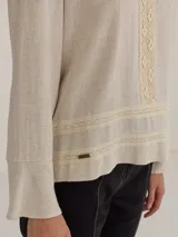 Camisa de tela suave y ligera en color crudo, con detalles de puntillas y cortes delicados que resaltan la figura.