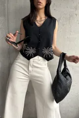 Chaleco negro de lino con bordado de palmeras en el ruedo, escote en V y cierre frontal con botones.