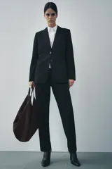 Blazer recta negra de Zara Woman Collection, con cuello solapa, manga larga con abertura y botones, bolsillos de plastrón en delantero, forro interior a tono y cierre frontal con botones.