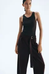 Pantalón sastrero marrón chocolate de punto, tiro alto con elástico oculto en la cintura y cierre decorativo. Cinturón cosido con anillas en D de metal en un lateral. Piernas ajustadas con pinzas para estilizar la silueta.