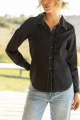 Camisa blanca con volados en los detalles, de corte clásico y manga larga.