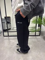 Pantalón de jogging negro oversize de algodón con cortes y logo bordado en blanco.