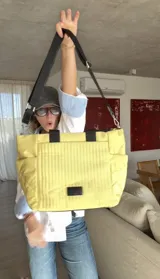 Cartera negra tipo tote bag con diseño capitoneado, doble asa corta y correa larga ajustable. Incluye bolsillos laterales y bolsillo frontal amplio.
