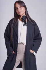 Tapado gris oscuro de corte oversize, con solapa clásica, hombros caídos, cierre con un botón central y bolsillos laterales funcionales.