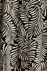 Vestido camisero midi de viscosa con estampado de hojas en blanco y negro, cuello camisero, botonadura frontal y cinturón ancho para atar extraíble. Mangas raglán largas con puños abotonados.