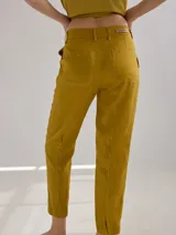 Pantalón largo de lino color marrón, con corte cigarette, tiro alto, bolsillos laterales y traseros con pespuntes a la vista, y etiqueta de cuero con logo en la cintura.