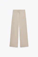 Pantalón de algodón color beige, de corte amplio y tiro alto, con cintura elástica ajustable con cordones y bolsillos laterales.