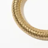 Pulsera rígida dorada con textura acanalada y cierre con piezas cilíndricas.