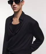 Camisa negra de poliéster con cuello inglés, manga larga, abotonada adelante y textura con rayas verticales.