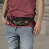 Riñonera negra con logo Caterpillar amarillo y estampado con el nombre de la marca en amarillo.