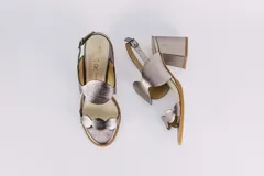 Sandalias plateadas de cuero con taco ancho y diseño de ondas en el empeine. Cierre con hebilla en el tobillo.