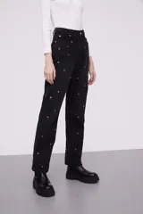 Pantalón gris medio de corte holgado, con detalles de aros decorativos sobre el tejido.