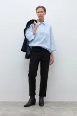 Camisa de popelina celeste con finas rayas blancas verticales, cuello camisero y abertura frontal con botones joya. Manga larga con puño ancho.