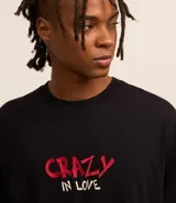 Remera negra de algodón con corte boxy, cuello redondo y mangas cortas. Estampado en la espalda de Lola Bunny besando a Bugs Bunny, con corazones y texto "Lola and Bugs Bunny".