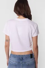 Remera blanca de jersey corte baby tee con cuello alto de ribb complemento. Estampa en delantero con la frase "30 million dolar babe" en color azul.