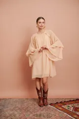 Vestido corto color salmón claro, de mangas largas con volados y corte suelto.